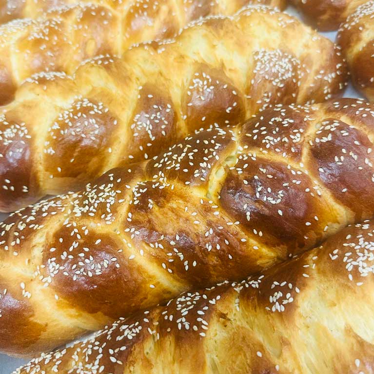 Freshly baked braided challah bread with sesame seeds