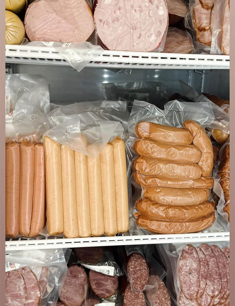 Assorted packaged sausages and meats in refrigerator display
