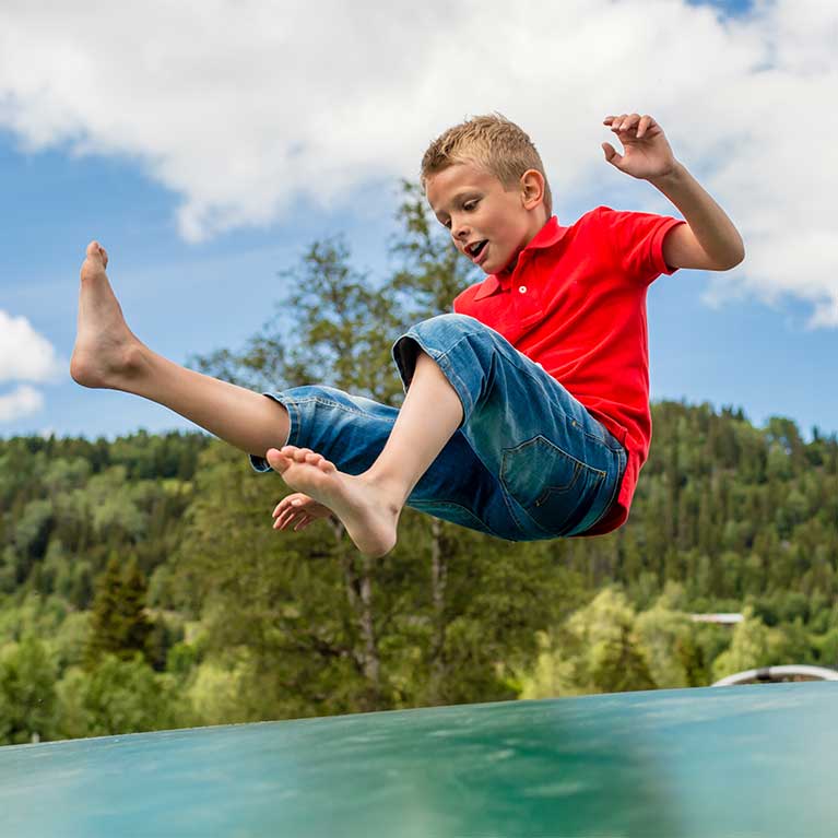 Boy jumping outdoors on trampoline