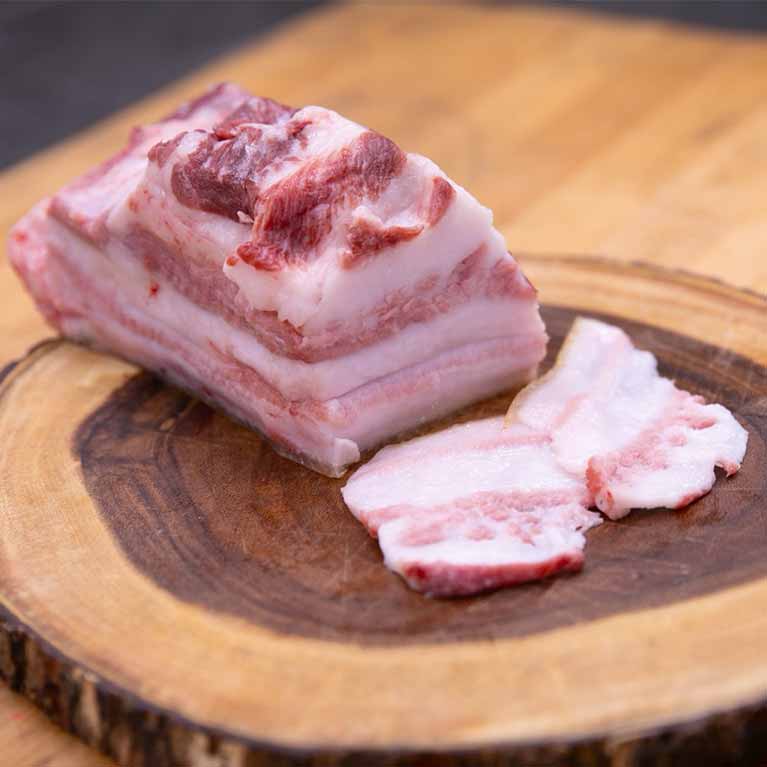 Raw pork belly slices on wooden board