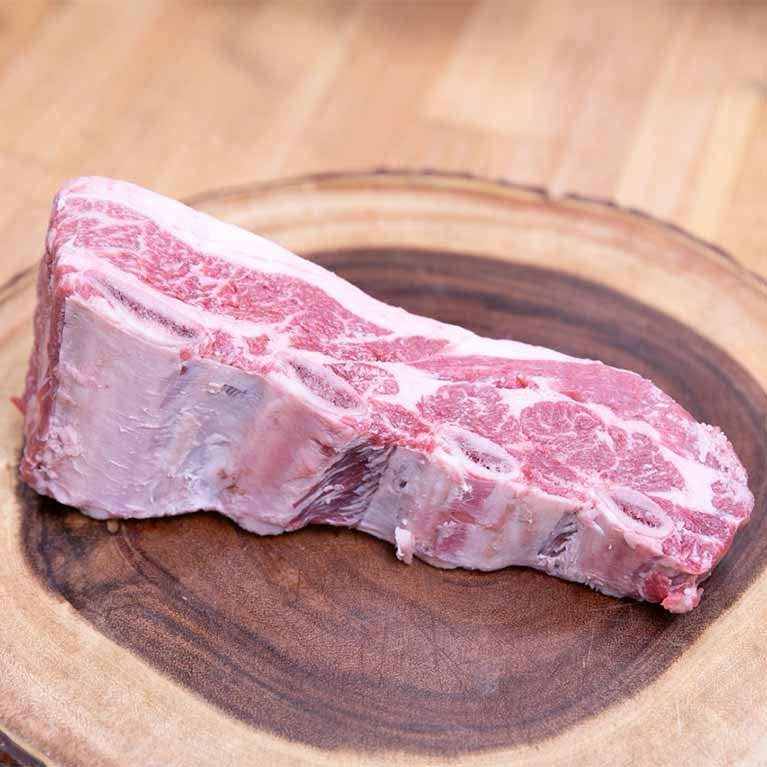 Raw beef short rib on wooden board
