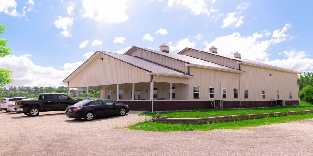 Large beige metal building with parked cars outside