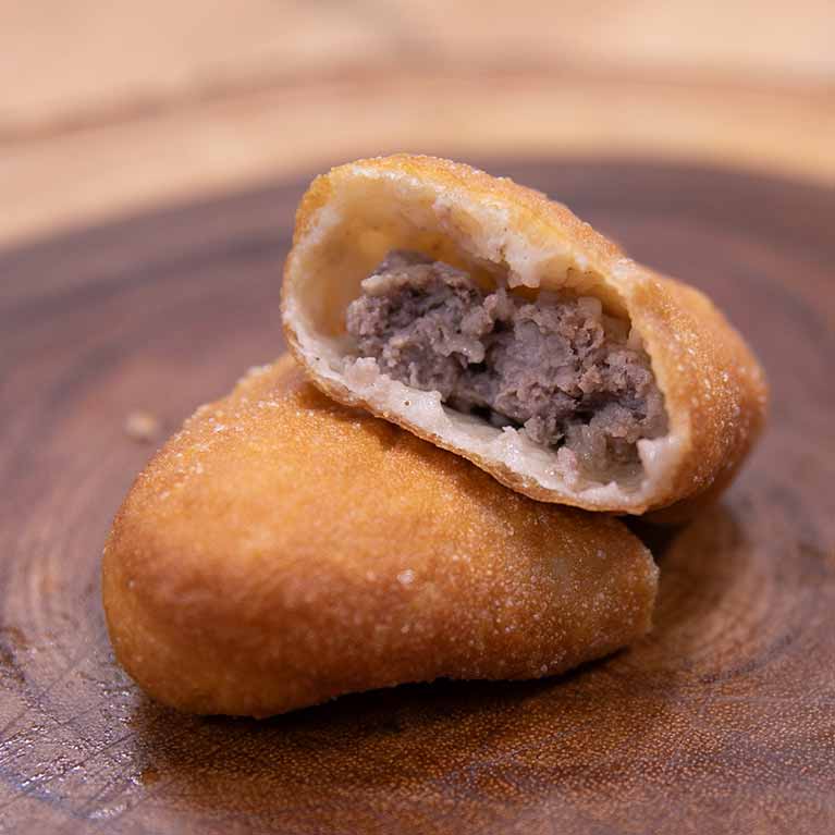 Fried empanada with beef filling on wooden board