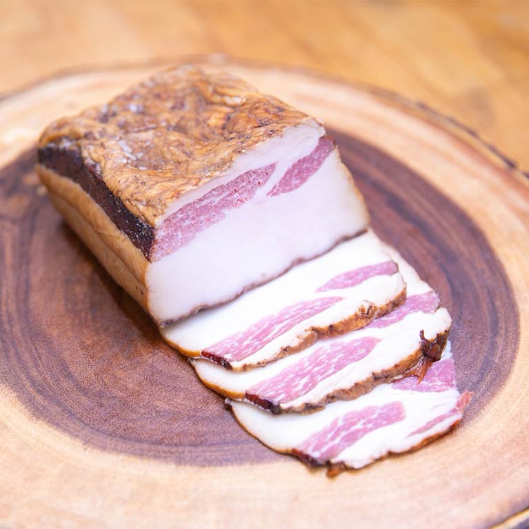Sliced smoked bacon on wooden plate